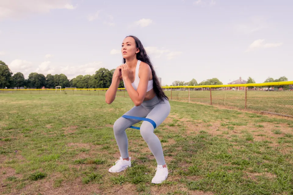 A woman doing a squat with a resistance band