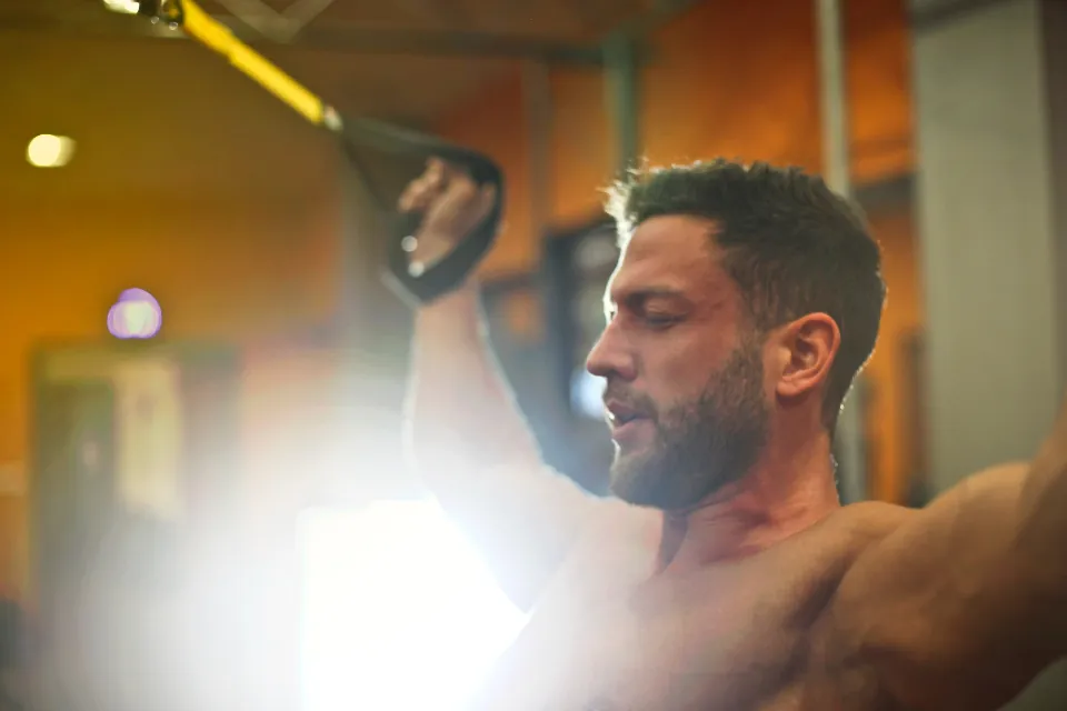 An athlete training with cables in warm light